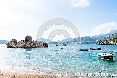 Special different rock in the adriatic sea in a small coast village in Budva. Small boats in the beach in turquoise blue water and Stock Photo