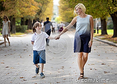 Special Kid and Loving Mom Walk Along Park Path Stock Photo
