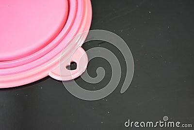 Pink folding and multifunctional rubber plate, a bowl with a plastic edging on a black glossy surface. Stock Photo