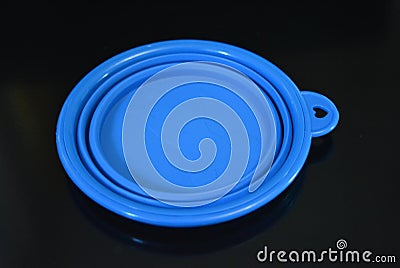 Blue folding and multifunctional rubber plate, a bowl with a plastic edging on a black glossy surface. Stock Photo