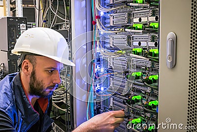 A specialist connects the wires in the server room of the data center. A man works with telecommunications. The technician Stock Photo