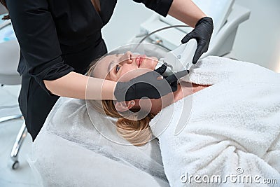 Specialist esthetician performs a hardware procedure for rejuvenating chin area Stock Photo