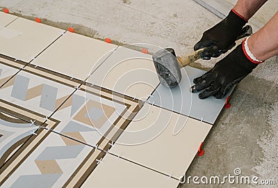 Specialist for laying tiles aligns the tiles with a carpenter`s Stock Photo