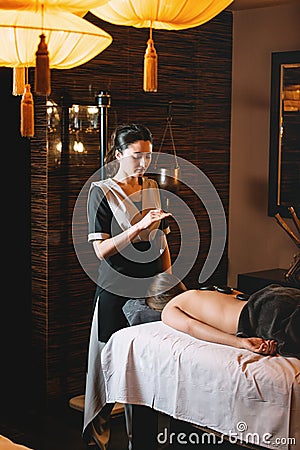 Young charming girl on a panchakarma procedure laying on a massage table. beautiful woman spending time at modern spa Stock Photo
