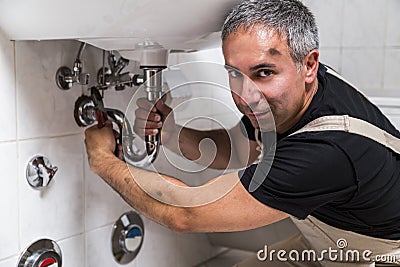 Specialist male plumber repairs faucet in bathroom Stock Photo