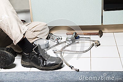 Specialist male plumber repairs faucet in kitchen Stock Photo