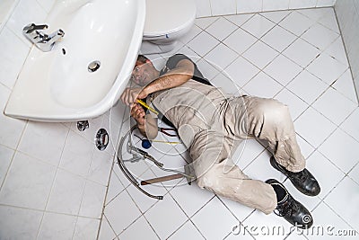 Specialist male plumber repairs faucet in kitchen Stock Photo