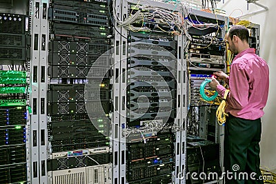 A specialist with optical Internet wires works in the server room. The system administrator switches the cables in the data center Stock Photo