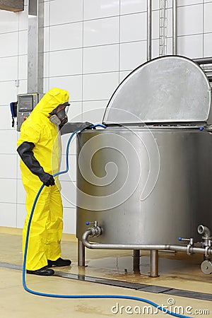 Specialist in uniform with hose in factory Stock Photo