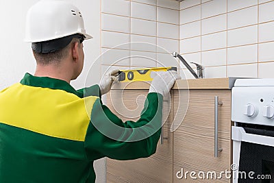 A specialist will check the evenness of the installation of kitchen furniture with a tool Stock Photo