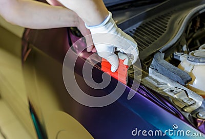 A specialist in wrapping a car with chameleon-colored vinyl film in the process of work. Stock Photo