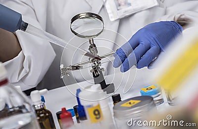 Specialized police taking shows blood in microscope holder to analyze in scientific laboratory Stock Photo