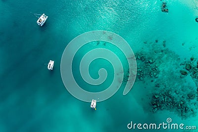 Spectacular aerial view of some yachts and small boats floating on a clear and turquoise sea, Seychelles in the Indian Ocean.Top Stock Photo