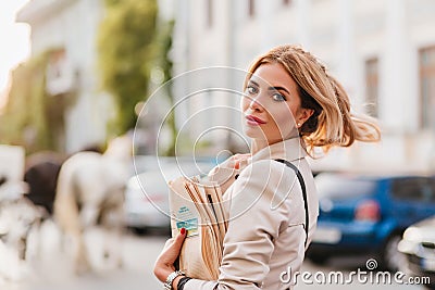 Spectacular blonde woman with hair waving hanging out alone carrying newspaper home. Outdoor portrait of interested lady Stock Photo