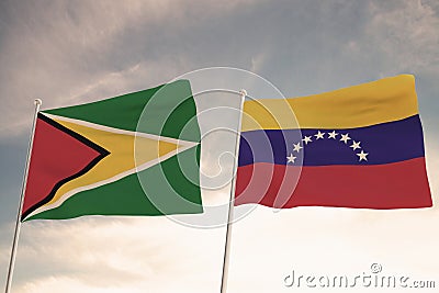 SPECTACULAR FLAGS OF GUYANA AND VENEZUELA WAVING WITH A BLUE SKY BACKGROUND CONFLICT RELTATIONSHIPS Stock Photo