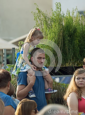 Spectator with girl on shoulders watch a show Editorial Stock Photo