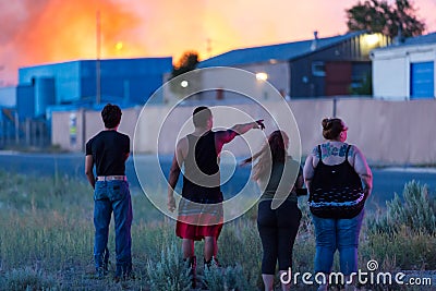 Spectators watch warehouse fire burning flames rage in the distance Editorial Stock Photo