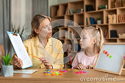 Speech training for kids. Female specialist training with smart little girl, teaching her right articulation exercises Stock Photo