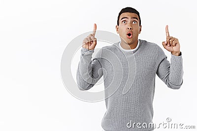 Speechless and curious, excited hispanic masculine guy, standing startled and astonished as pointing fingers up folding Stock Photo