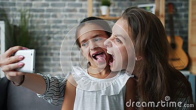 Speelende moeder neemt selfie met verachtelijke kleindochter die thuis plezier heeft stock footage Speelende moeder neemt selfie met verachtelijke kleindochter die thuis plezier heeft stock footage