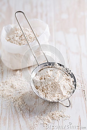 Spelt flour in sifter in flour bag on white wooden table Stock Photo