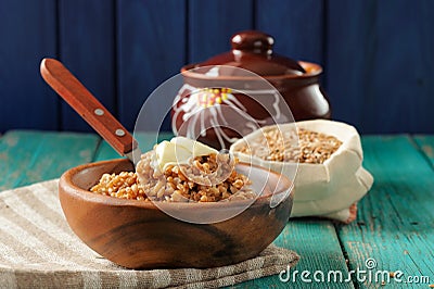 Spelt porridge buttered in wooden bowl and raw spelt in linen ba Stock Photo