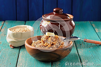 Spelt porridge buttered in wooden bowl and raw spelt in linen ba Stock Photo
