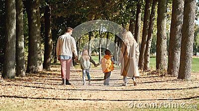 Spending time in nature. Back view of a family holding hands and walking in the park Stock Photo