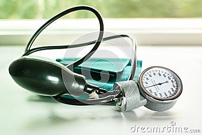 Sphygmomanometer on the working table of a cardiologist. Green tonometer for measuring blood pressure. Stock Photo