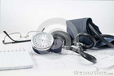 Sphygmomanometer on the working table of a cardiologist. Tonometer, electrocardiogram and notepad for records. Stock Photo