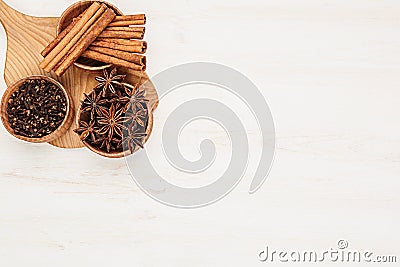Spices - aniseed, cinnamon, cloves in wooden bowls on a wood white background. Stock Photo