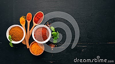 Spices and herbs on a wooden board. Pepper, salt, paprika, basil, turmeric. On a black wooden chalkboard. Stock Photo