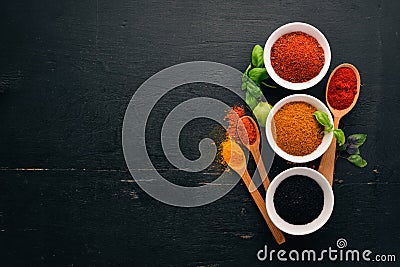 Spices and herbs on a wooden board. Pepper, salt, paprika, basil, turmeric. On a black wooden chalkboard. Stock Photo