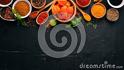 Spices and herbs on a wooden board. Pepper, salt, paprika, basil, turmeric. On a black wooden chalkboard. Stock Photo