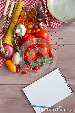Spices, pasta and vegetables around notebook. Stock Photo