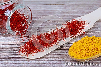 Spices on a wooden background. Saffron and turmeric on a wooden spoon Stock Photo