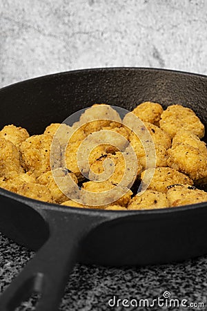 Spicy coated southern fried chicken bites in a cast iron frying pan. Stock Photo