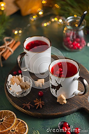 Spicy cranberry tea in two white mugs on a wooden board on a concrete green background in Christmas style. Merry Christmas concept Stock Photo
