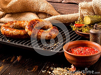 Spicy homemade sausages pork and beef sausages, on a wooden background, with sauce, spices and pickled cucumber . Template in Stock Photo