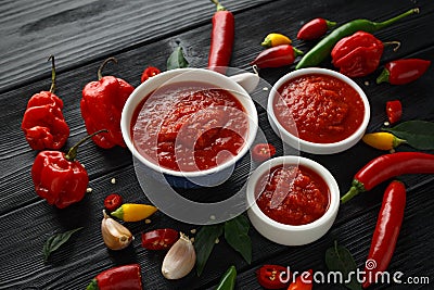 Spicy hot sweet chili sauce with mix of chilli pepper, garlic and tomatoes on rustic wooden background Stock Photo