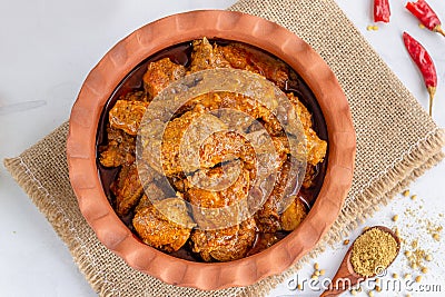 Spicy Indian Chicken Curry in a Clay Pot Garnished with Onion, Lemon and Cilantro Top Down Photo Stock Photo