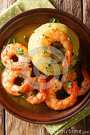 Spicy mofongo with plantains, garlic and chicharron served with shrimp and broth close-up on the table. Vertical top view Stock Photo