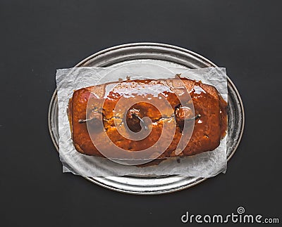 Spicy pear cake with caramel topping on a silver dish on dark surface Stock Photo