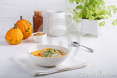 Spicy pumpkin soup served with pumpkin seeds and parsley. Bowl with autumn squash soup on white table Stock Photo