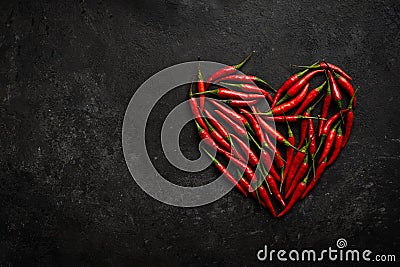 Spicy red chili pepper in the shape of a heart on a dark stone background Stock Photo