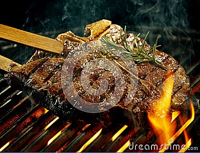 Spicy t-bone steak grilling over a summer barbecue Stock Photo