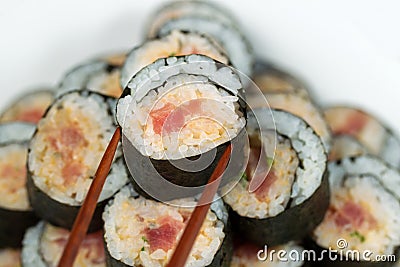 Spicy Tuna Roll being selected with Chopsticks Stock Photo