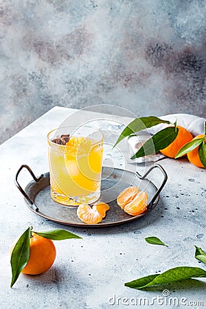 Spicy winter yellow orange cocktail or mocktail with fresh tangerines and anise on grey background. Stock Photo