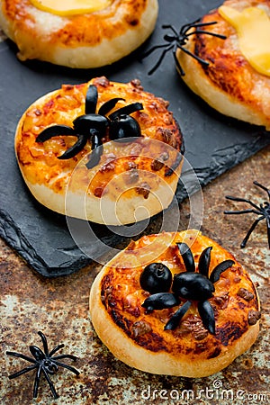 Spider pizza on Halloween. Homemade mini pizza decorated with olives in the form of a spider for kids treats Stock Photo