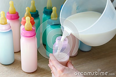 Spill milk into bottles with colored lids and nipples Stock Photo